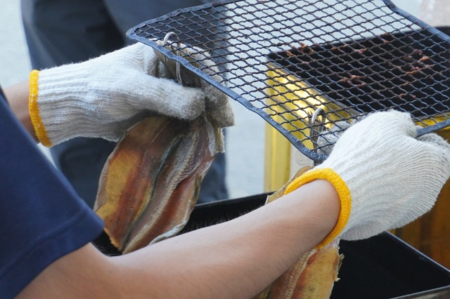 写真：フックに魚をくくりつけ、網にかける作業