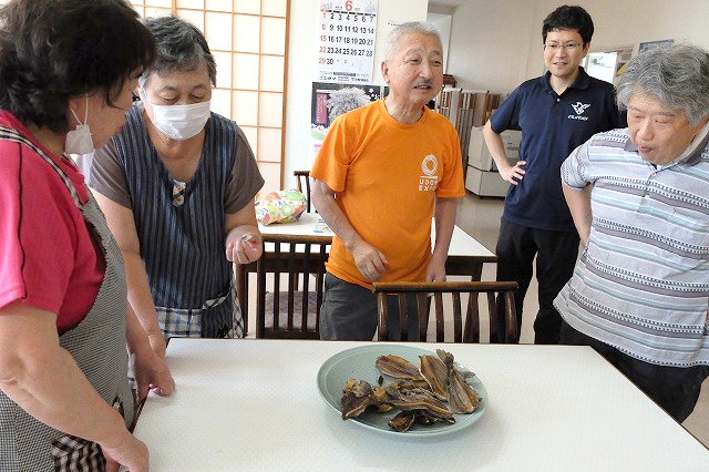 写真：いぶした魚を試食する住民
