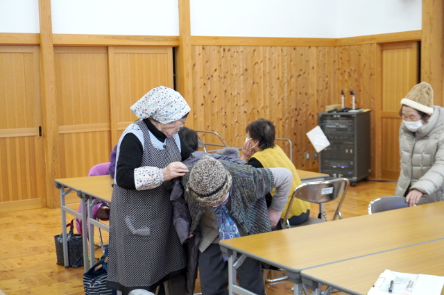 画像：住民がコートを着るのを手伝うスタッフ